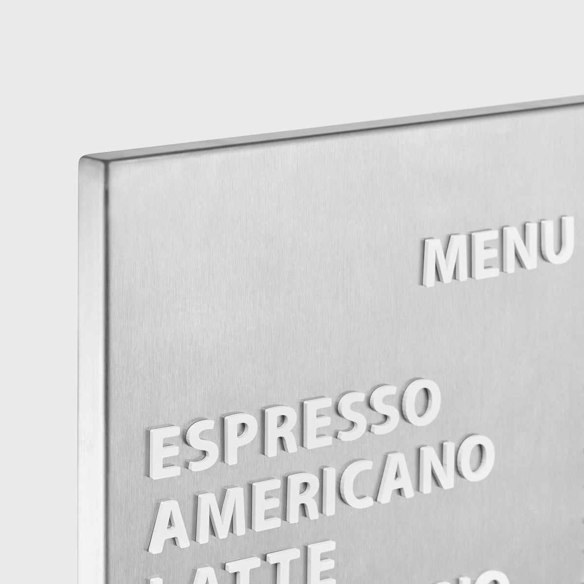 Stainless steel menu board with white acrylic menu text displayed on a wall