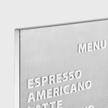 Stainless steel menu board with white acrylic menu text displayed on a wall